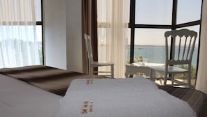 Una habitación de hotel con una cama, una silla y vista al mar.