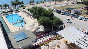 Un hotel con piscina, mobiliario exterior y zona de estacionamiento.