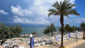 Un restaurante frente al mar con terraza, palmeras y vistas al océano.