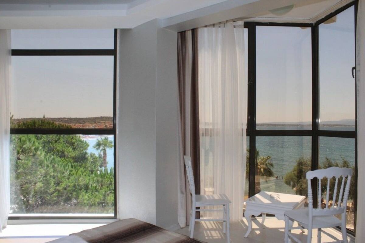 Un balcón con mesa y sillas, con vistas panorámicas a árboles y agua.