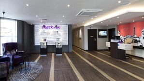 A hotel lobby with a reception desk, check-in counters, a seating area with a sofa and chairs, and a large wall with motivational phrases. - Premier Inn Bridlington Seafront (Bridlington)
