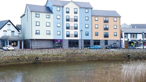 A multi-story hotel with a stone facade, a flat roof, and a water body in front. - Premier Inn Bude (Bude)