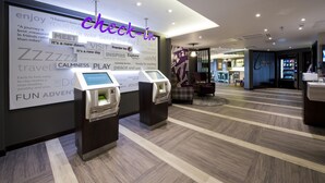 A hotel lobby with a check-in kiosk, a reception desk, and a seating area. - Premier Inn Leeds Headingley (Leeds)