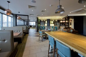 A modern restaurant interior with booths, a bar area, and a seating arrangement. - Premier Inn Leeds Headingley (Leeds)