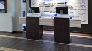 Un comptoir d’accueil d’hôtel avec une enseigne indiquant « Premier Inn » et un mur orné de citations inspirantes et du logo de l’hôtel.