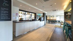 Un área de bar moderna con mostrador, asientos y un tablero de menú.