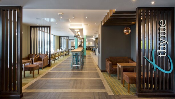 A modern hotel lobby with a long corridor, wooden partitions, and seating areas. - Premier Inn Slough West - Slough Trading Estate (Slough)