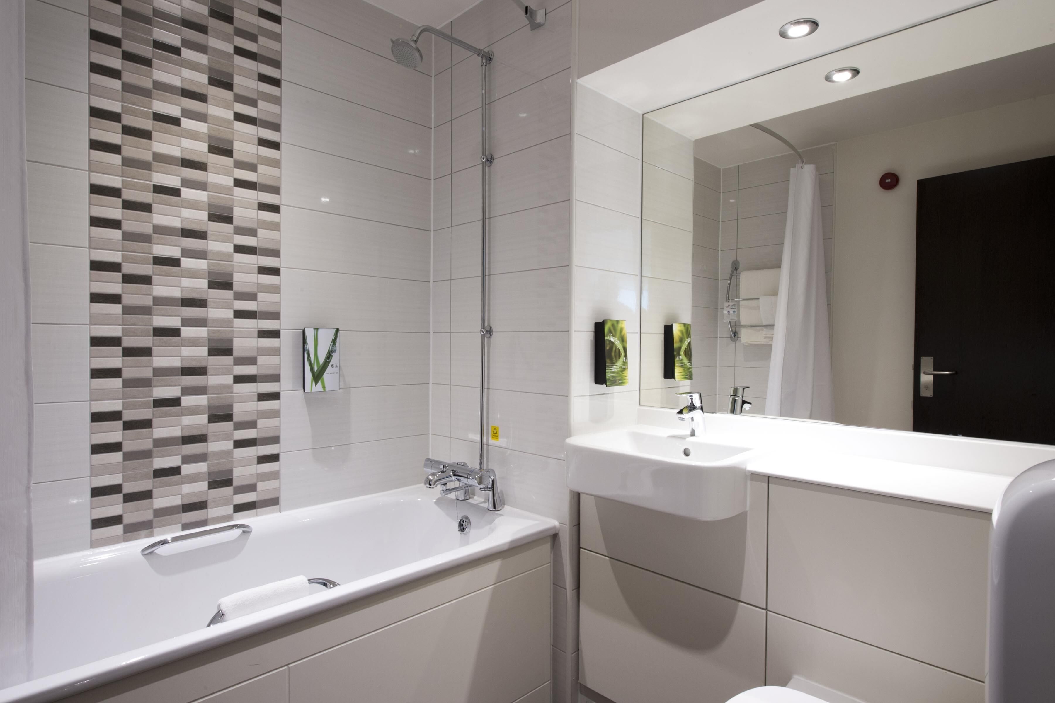 A modern bathroom with a freestanding bathtub, a large mirror, and a shower area.