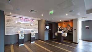 A hotel lobby with a large wall sign, a reception desk, a self-service kiosk, and a bike rental station. - Premier Inn Slough West - Slough Trading Estate (Slough)