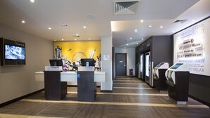 A hotel reception area with a reception desk, a digital screen, and a wall with motivational words. - Premier Inn Southampton - Cumberland Place (Southampton)