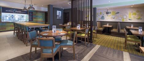 A restaurant with a bar area, multiple seating options, and a wall with food illustrations.