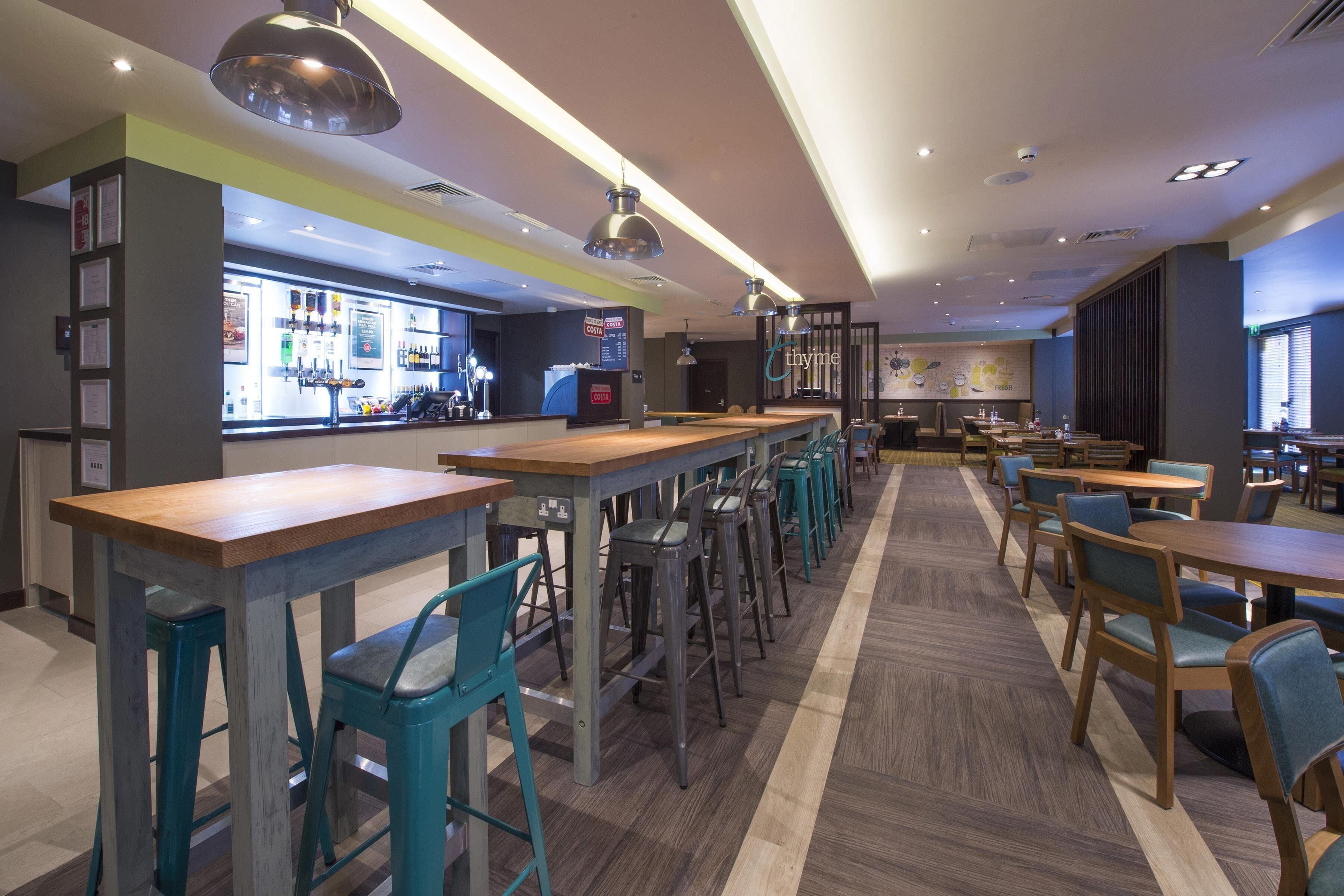 A modern bar area with multiple seating options, a counter with a menu, and a barista station.