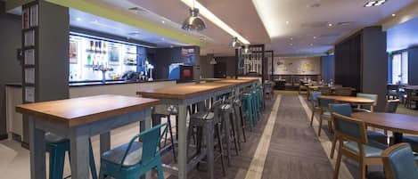Un espace bar moderne offrant différentes options de sièges, un comptoir avec un menu et un poste de travail pour le barista.