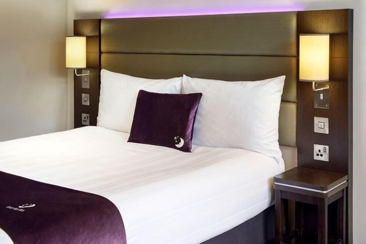 Ett hotellrum med en stor säng, två sänglampor och en sänggavel med inbyggd belysning.