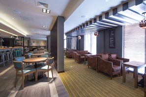 A modern hotel lobby with a bar area, seating arrangements, and a patterned carpet. - Premier Inn Southampton - Cumberland Place (Southampton)