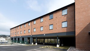 A multi-story building with a covered parking area and a brick facade. - Premier Inn Ulverston (Ulverston)