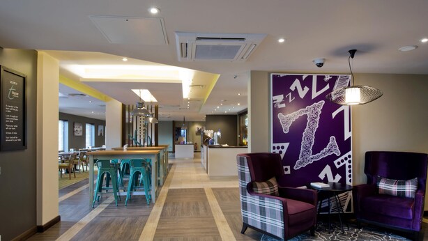 A hotel lobby with a reception desk, seating area, and a patterned wall. - Premier Inn Ulverston (Ulverston)