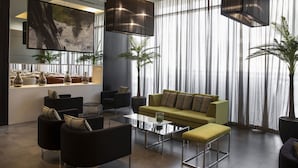 A modern living room with a sofa, armchairs, a coffee table, and a large painting on the wall.