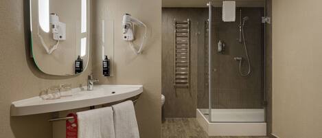 A modern bathroom with a sink, mirror, hairdryer, and shower.