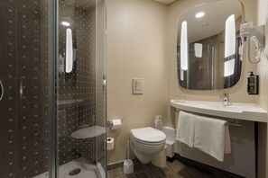 A modern bathroom with a glass shower enclosure, a toilet, a sink with a towel, and a large mirror. - ibis Kyiv Railway Station (Kyiv)