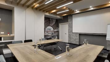 Un salón de conferencias con una larga mesa, sillas, una pantalla de proyector y un amplio ventanal con vistas.