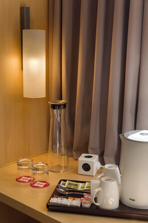 A hotel room's minibar with a coffee maker, tea kettle, and glass containers labeled "ibis". - ibis Kyiv Railway Station (Kyiv)
