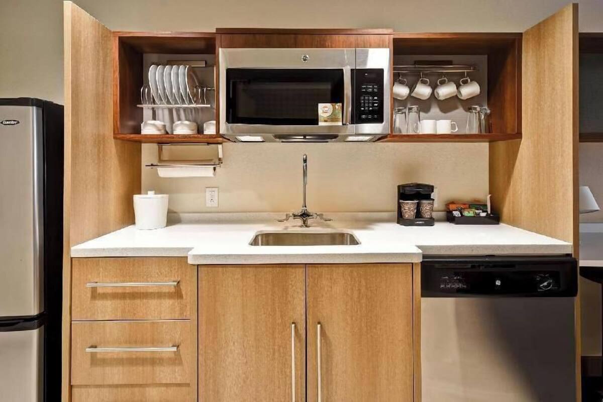 A compact kitchen with a built-in microwave, a sink, and wooden cabinets.