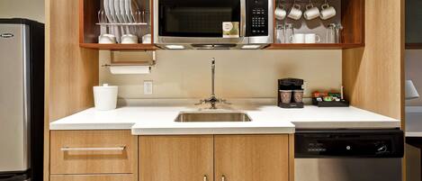 A compact kitchen with a built-in microwave, a coffee maker, and a dishwasher.