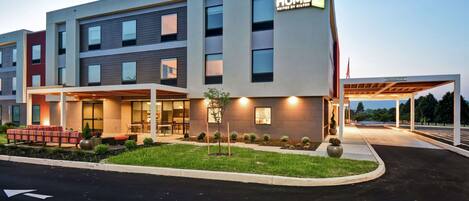 A multi-story hotel with a modern design, featuring a well-lit entrance and outdoor seating area.