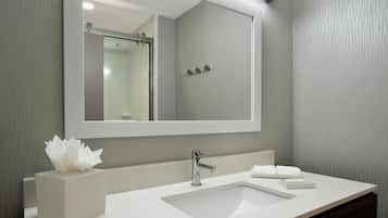 A modern bathroom with a large mirror, a white sink, and a towel rack.