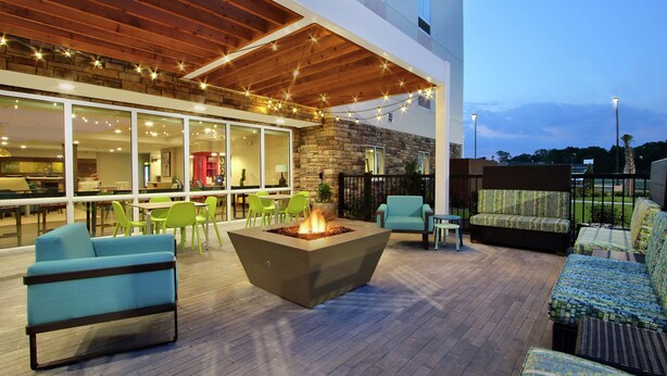 Un patio al aire libre con un brasero, asientos e iluminación colgante.