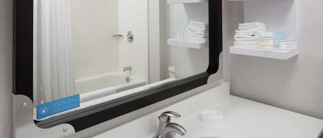 Un baño con un lavamanos blanco, un espejo y un perchero con toallas dobladas con esmero.