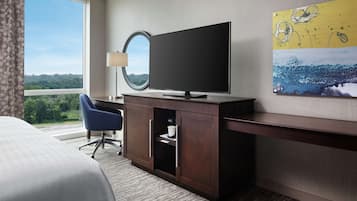 Une chambre d’hôtel équipée d’un grand téléviseur à écran plat, d’un bureau avec une lampe, d’une chaise bleue et d’un lit.