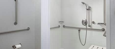 Baño con ducha, barras de apoyo, inodoro y secamanos.