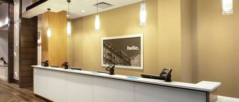 Una recepción con un letrero que dice 'hello', un teléfono y una pantalla digital.