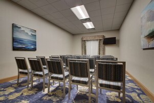 Un salón de conferencias con filas de sillas, una televisión de pantalla plana y obras de arte en las paredes.