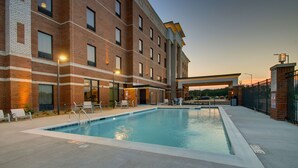 A swimming pool with lounge chairs and a brick building in the background. - Hampton Inn Sneads Ferry North Topsail Beach (Sneads Ferry)