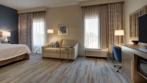 A hotel room with a bed, a sofa, a desk with a computer, and a TV. There are curtains on the windows and a picture on the wall. - Hampton Inn Sneads Ferry North Topsail Beach (Sneads Ferry)