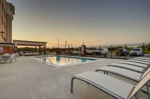 Una piscina al aire libre, sillones reclinables de piscina