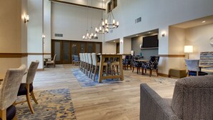 A spacious hotel lobby with a long dining table, multiple chairs, and a television screen. - Hampton Inn Sneads Ferry North Topsail Beach (Sneads Ferry)