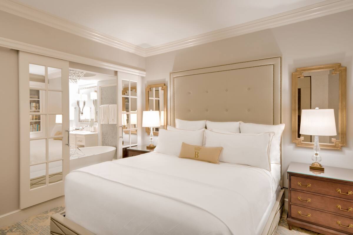 Um quarto espaçoso com uma cama grande, um closet amplo, uma toucador com espelho e uma mesa de cabeceira com abajur.