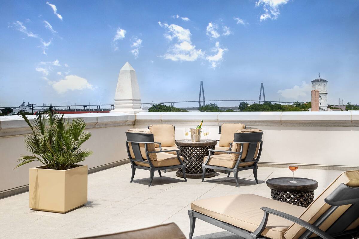 Terraço no telhado com área de estar ao ar livre, um vaso de planta e vista para uma ponte e torre.