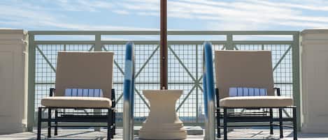 A poolside area with two lounge chairs and a large umbrella.