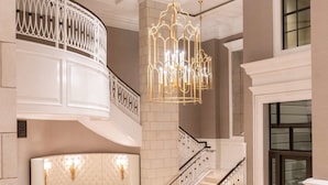 Un interior imponente con una escalera curva, un candelabro y un área de descanso.