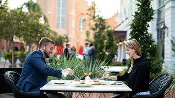 A couple dining at an outdoor table with a view of a church and other buildings in the background.