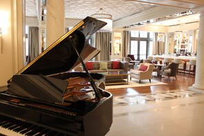 A grand piano in a spacious, elegantly furnished living area with a bar and seating arrangements.
