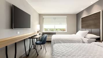 Habitación de hotel con cama, escritorio, silla, televisión y ventana con vistas.