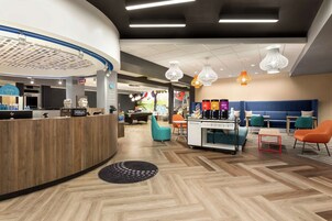 A hotel lobby with a reception desk, seating area, and a kitchenette.