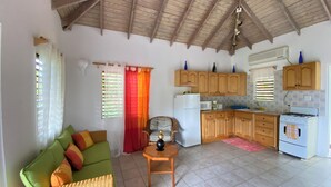 Un espacio habitable compacto con kitchenette, un sofá, una mesa de comedor y un ventilador de techo.