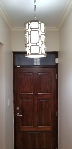 A wooden door with a modern pendant light fixture above it. - New Kingston Guest Apartment at Eight (Kingston)